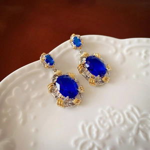 Boucle d'oreille vintage bicolore avec pierre bleue ovale sur un plateau en céramique