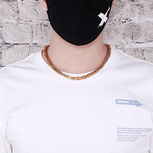 Detail einer goldenen V-förmigen Byzantiner-Halskette getragen von einem Modell im Streetwear-Stil