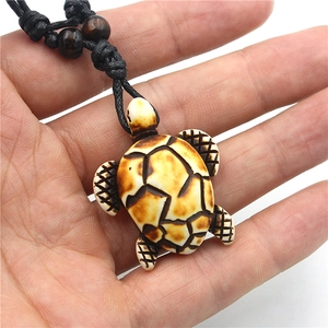 Resin sea turtle pendant necklace with bone-like texture on black braided cord