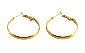 Macro detail of gold circular hoop earrings with a matte brushed metallic finish