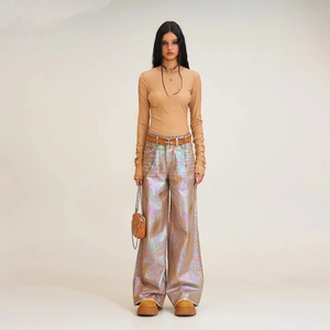 Détail d'un haut ajusté à manches longues côtelé avec un pantalon laser irisé et un mini sac