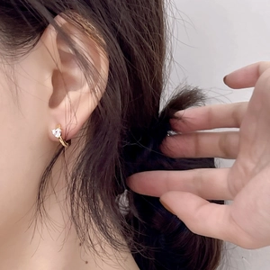 Close-up of model wearing gold hoop earrings with heart-shaped crystal zircon detail