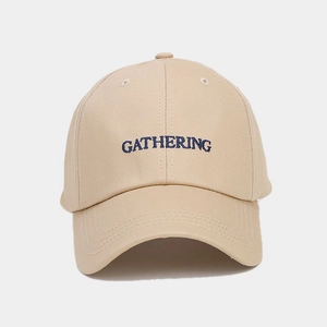 Detail shot of khaki cotton baseball cap featuring blue Gathering letter embroidery