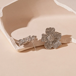 Macro detail of silver floral stud earrings with pavé diamonds on stone pedestal