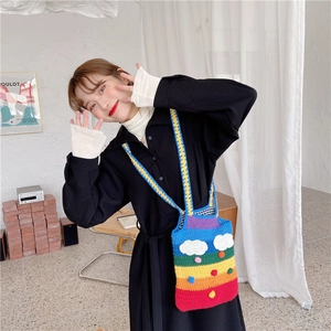 Detail of handmade knit rainbow shoulder bag with colorful stripes and white cloud patch