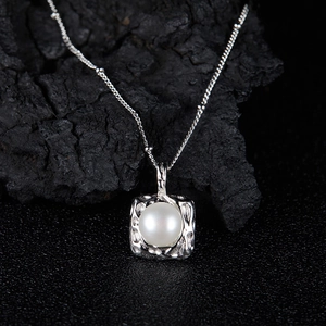 Macro view of a freshwater pearl necklace pendant on a textured black stone