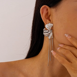 Dettaglio macro di orecchini a fiore in metallo argento con lunghe nappe pendenti