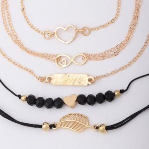 Detailed flat lay of 5-piece gold and black bracelet set with heart and leaf charms