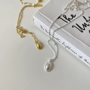 Close-up of gold and silver S925 sterling silver oval pendant necklaces on a book