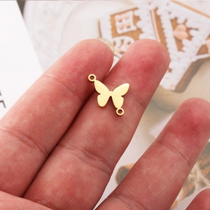 Golden butterfly jewelry connector with double holes held by fingers for DIY crafts