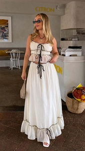 Detailed texture of white pleated crop top with black tie straps and long skirt