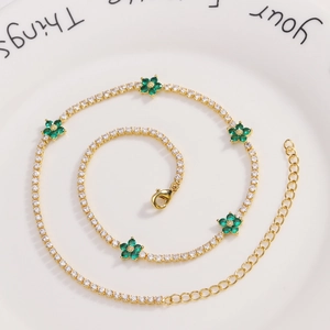 Detailed macro view of gold-plated tennis necklace with green zircon flower accents