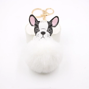 Detail of a fluffy white faux fur pompom French Bulldog bag charm with gold clasp