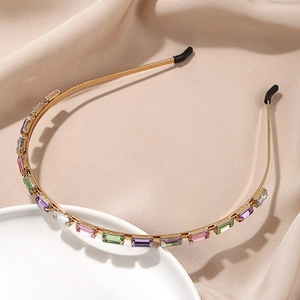 Detail of gold alloy headband with colorful rectangular crystals on beige fabric