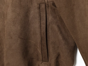 Detailed macro view of welt pocket stitching on dark brown suede bomber jacket