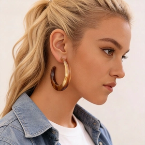 Brown resin tortoiseshell C-shape hoop earrings worn by a model in a side profile view
