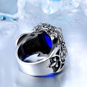 Detail of silver gothic ring with deep blue gemstone and intricate side carvings