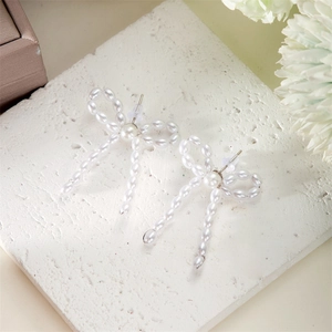 Detailed close-up of bowknot faux pearl earrings with elegant beaded tassels and metal studs