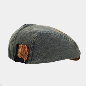 Close-up of vintage denim beret featuring orange plaid patchwork and distressed texture