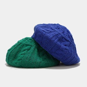 Detailed cable knit texture of emerald green and royal blue winter beret hats