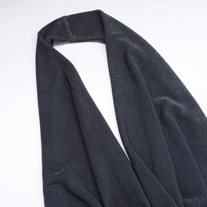 Dettaglio dell'abito grigio scuro con scollo all'americana e texture in maglia a pieghe