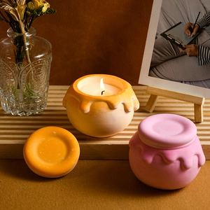 Candele profumate a forma di vasetto di miele rosa e arancio su assi di legno