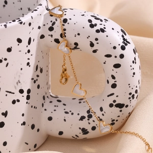 Detail of 18K gold-plated heart bracelet with white shell inlays on a ceramic cup