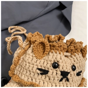 Detail of a handmade crochet lion bag with beige yarn and brown mane accents