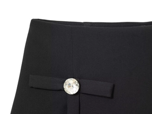 Close-up of black skirt shorts with elegant bow detail and sparkling rhinestone button