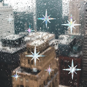 Close-up of holographic rainbow star window film on wet glass with city skyline view