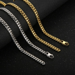 Detail of silver and gold Cuban link chains with lobster clasps on a dark textured background