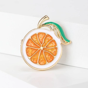 Vibrant enamel orange slice brooch with golden metal frame and green leaf detail
