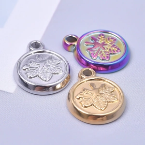 Macro view of round stainless steel charms with leaf patterns in gold, silver and rainbow