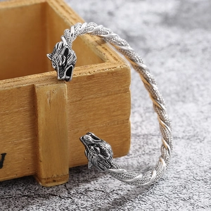 Macro detail of retro stainless steel wolf head bracelet with woven wire texture on wood