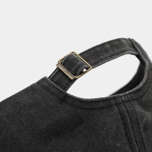 Macro detail of bronze metal adjustable buckle on dark grey washed cotton baseball cap