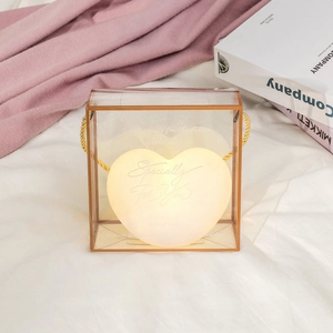 Detail of warm glowing heart night light in a transparent gift box with gold handle