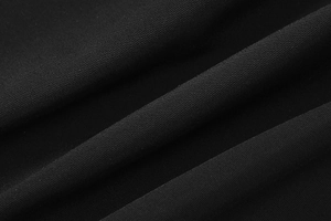 Gros plan sur un tissu noir de qualité montrant la texture fine et le drapé fluide