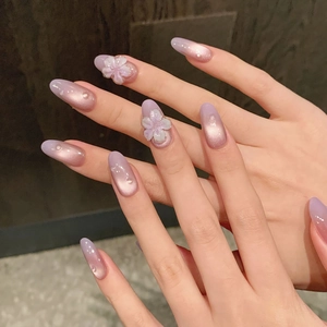 Long almond press-on nails with purple cat-eye gradient and 3D floral pearl accents