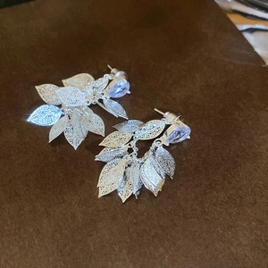 Close-up of silver hollow leaf tassel earrings with purple cubic zirconia stones