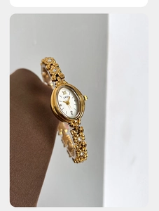 Detailed close-up of a vintage gold floral bracelet watch with an oval dial and rhinestones