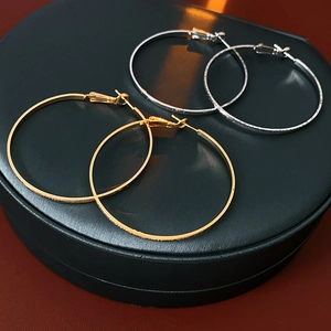 Detailed view of polished gold and silver hoop earrings on a black leather stand display