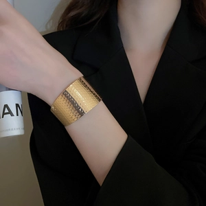 Detail of wide golden cuff bracelet with premium hammered texture on a model