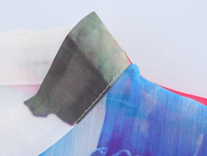 Close-up of crew neckline on a floral chiffon blouse with ruffled edges and tie-dye pattern