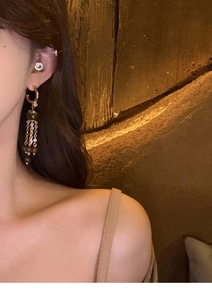 Detail of vintage gold tiger eye stone tassel earring worn on ear with high texture