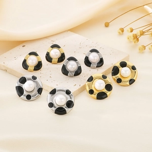 French vintage enamel and pearl stud earrings displayed on elegant stone and fabric
