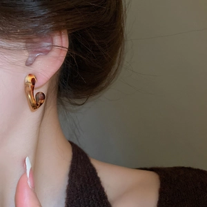 Close-up of retro C-shape amber leopard resin earring worn on a model's ear