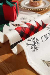 Detail of Christmas table runner with rustic snowflake and patterned tree prints on linen cloth