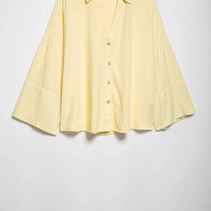Pale yellow linen-blend wide sleeve shirt with V-neck and wooden buttons on white background