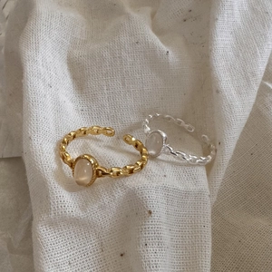 Detail of S925 silver chain rings with oval moonstone on rustic linen background