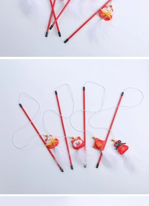 Detail of red Chinese New Year cat wand toy with festive embroidery and white feathers